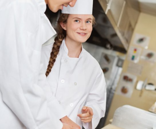 Young chefs preparing food in commercial restaurant kitchen